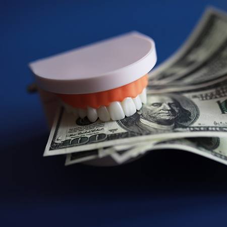A set of false teeth clamped down on several $100 bills
