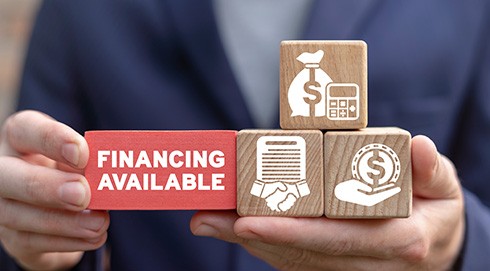 hands holding blocks with financing-related icons on them