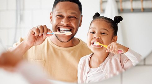 a father and daughter brushing their teeth