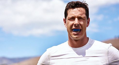 an athletic man wearing a blue mouthguard