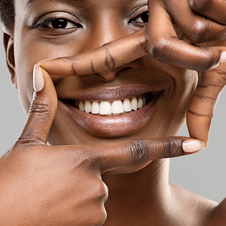 Woman framing her bright white smile with four fingers