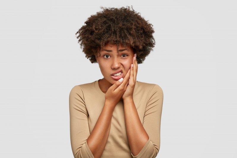 A woman holding her cheek while suffering a toothache